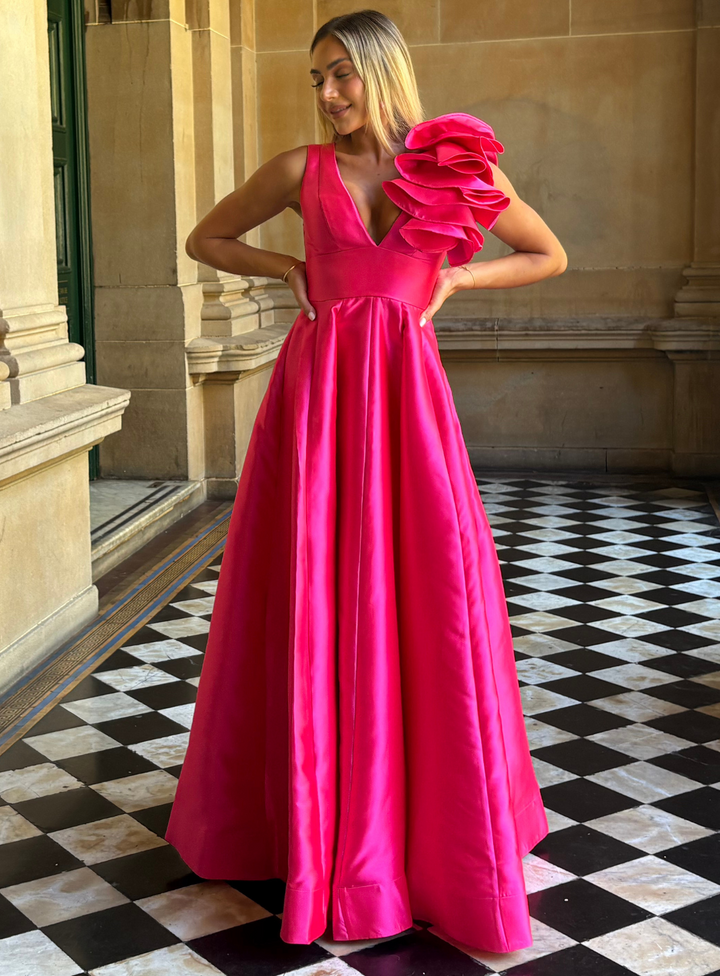 Mother of the bride hot pink ballgown with v-neckline and statement ruffle detail on the shoulder. 